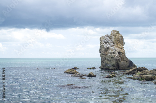 Turquoise sea water surface and big rock