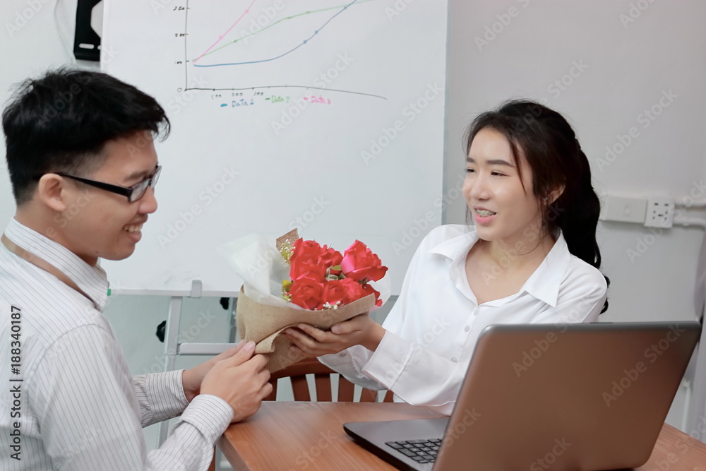 Φωτογραφία Happy young Asian woman accepting a bouquet of red roses from boyfriend in office on valentine's day