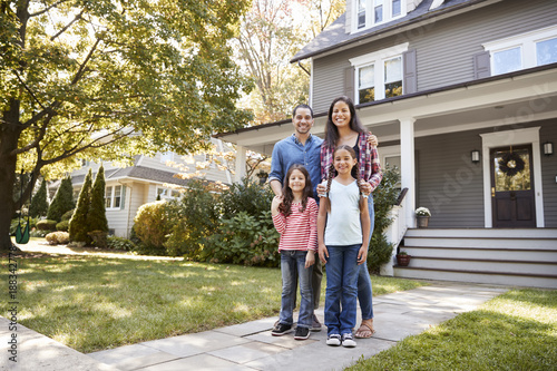 Obraz na plátně Portrait Of Smiling Family Standing In Front Of Their Home