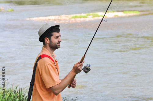 Man casts a hook on the river. Man fishing on wild river