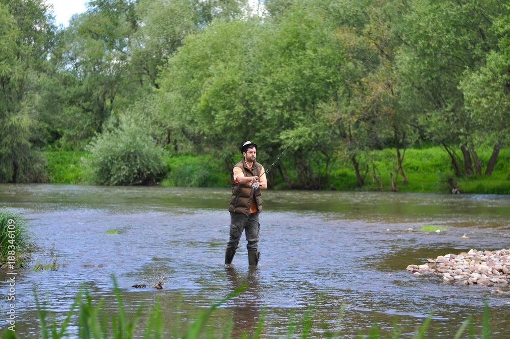 Man casts a hook on the river. Man fishing on wild river