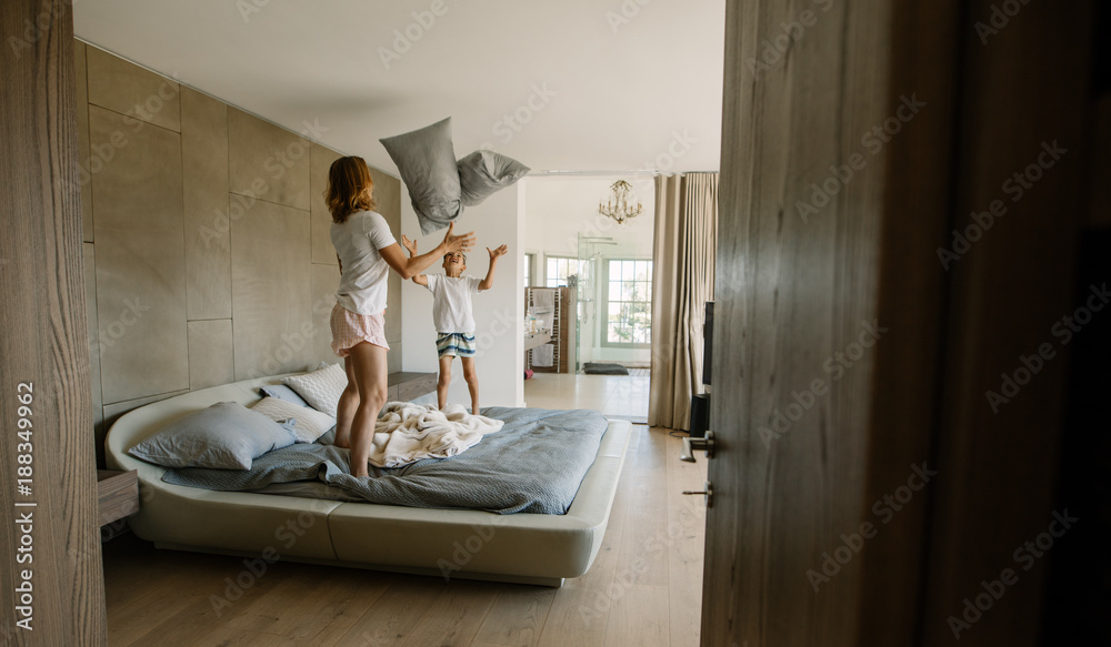Obraz premium Mother and son playing with pillows in bedroom