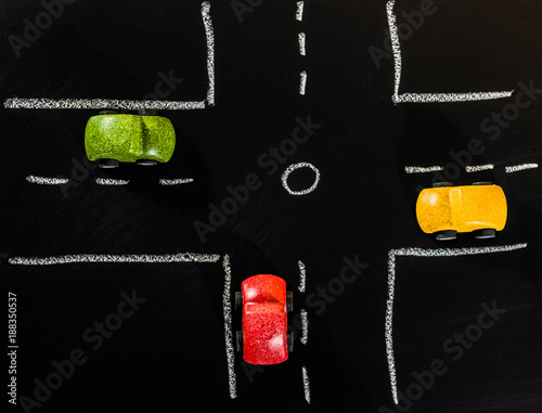 Red Green and Yellow wooden car toys stop on crossroad of chalk board