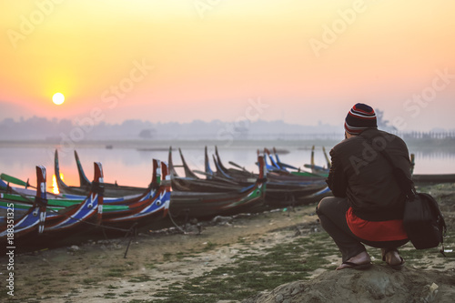 Selective focus on tourist taking picture of sunrise in Taungthaman Lake near Amarapura, Myanmar