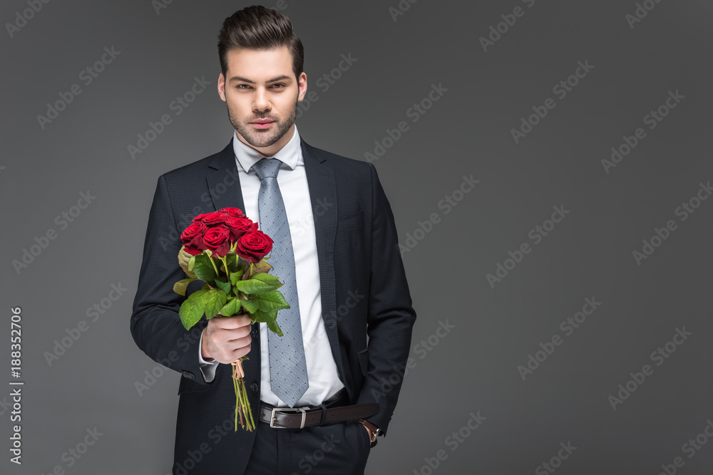 handsome man holding bouquet of red roses, isolated on grey handsome man holding bouquet of red roses, isolated on grey