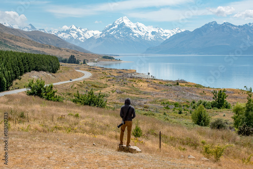 Photos Young male photographer in hoody watching at Mount Cook, one of the most famous snowy mountain at peter’s lookout in South Island, New Zealand
