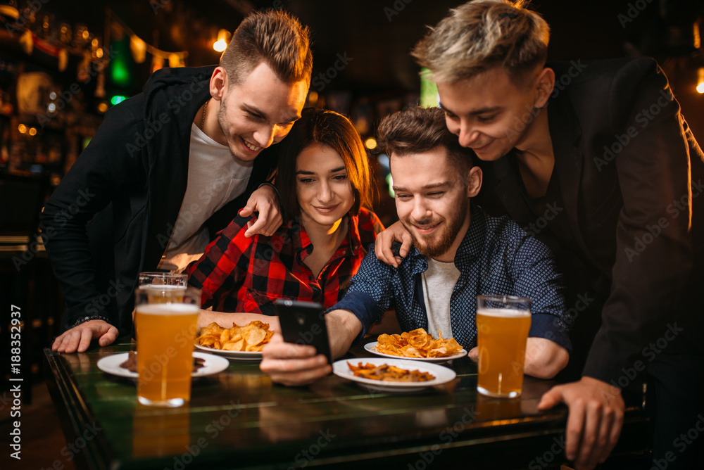 Fun company watches photo on phone in a sport bar