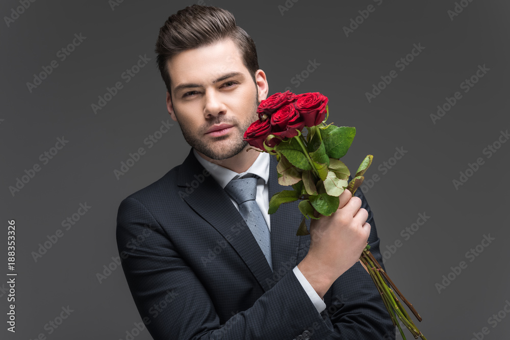 handsome man in suit holding bouquet of red roses, isolated on grey handsome man in suit holding bouquet of red roses, isolated on grey