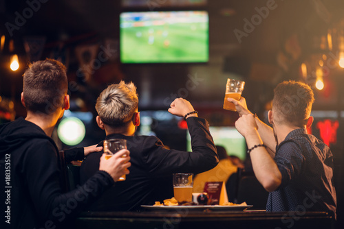 Foto Three men watches football on TV in a sport bar