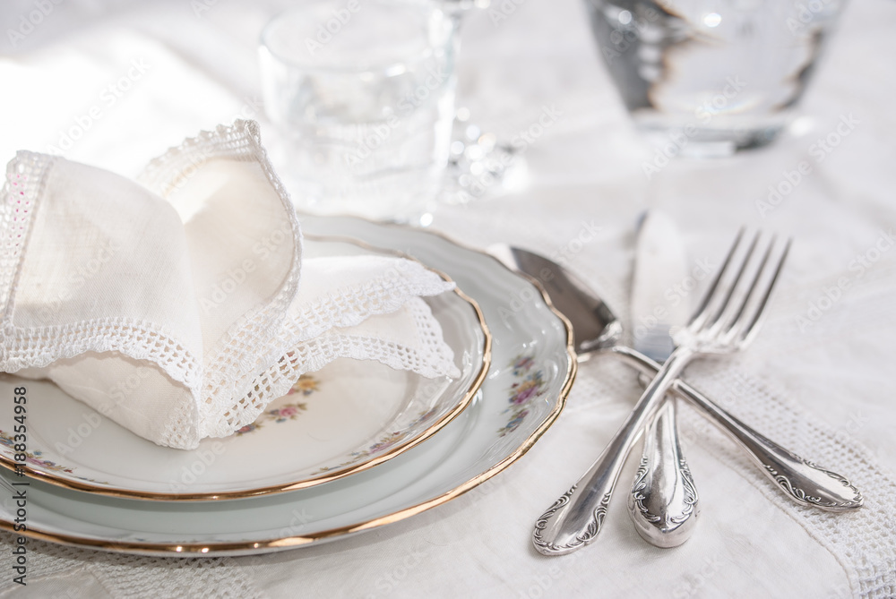 Luxury dinner set with silverware, elegant porcelain dishes, crystal  glassware and vintage lace napkins foto de Stock | Adobe Stock
