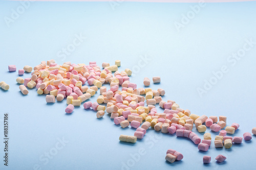 Marshmallows on light blue background with copyspace. Background or texture of colorful mini marshmallows. Winter food background concept.