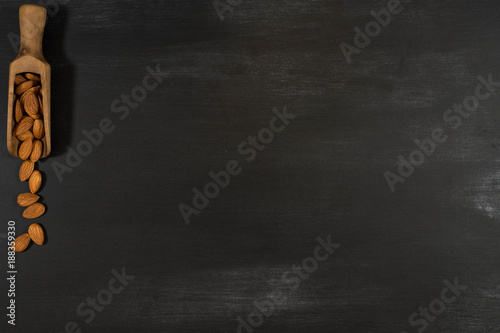 Almonds in a wooden scoop in a black chalkboard.
