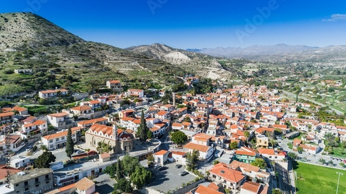 Aerial bird eye view of Kalavasos village valley, Larnaca, Cyprus. A traditional town with ceramic roof tiles houses, a greek orthodox christian church and muslim mosque around hills, from above. 