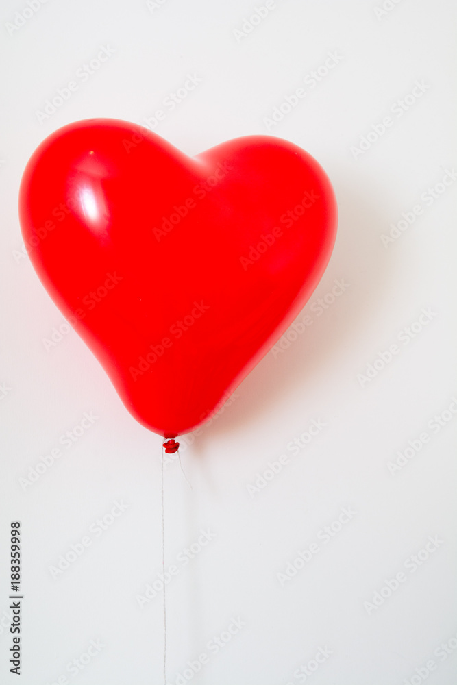 Red heart shaped balloon on a string isolated on white