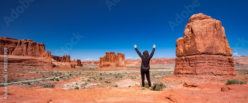 woman with raised arms facing monument valley
