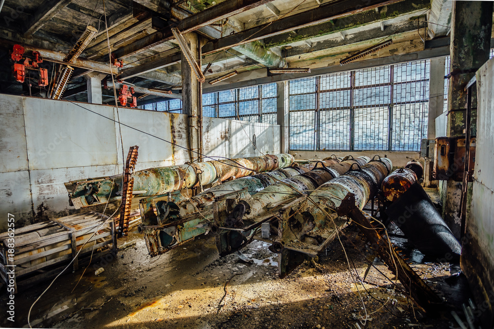 Old rusted submarine torpedoes in abandoned torpedo factory. Rear view