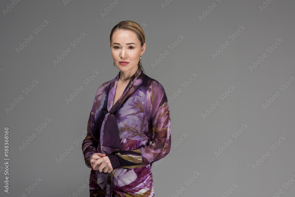 portrait of beautiful fashionable kazakh woman looking at camera isolated on grey