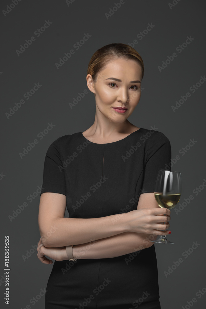 beautiful kazakh woman holding glass of wine and looking at camera isolated on grey beautiful kazakh woman holding glass of wine and looking at camera isolated on grey