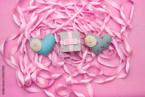 Fototapeta Naklejka Na Ścianę i Meble -  Textile heart gift against a Coil of decorative satin ribbons of pink color.