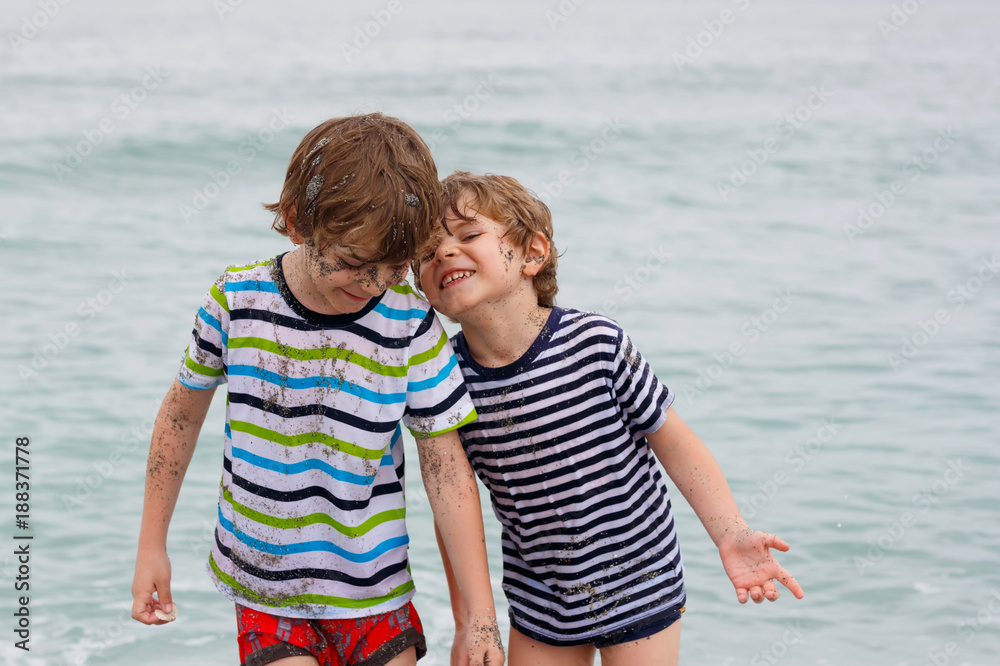 Two happy little kids boys running on the beach of ocean Two happy little kids boys running on the beach of ocean