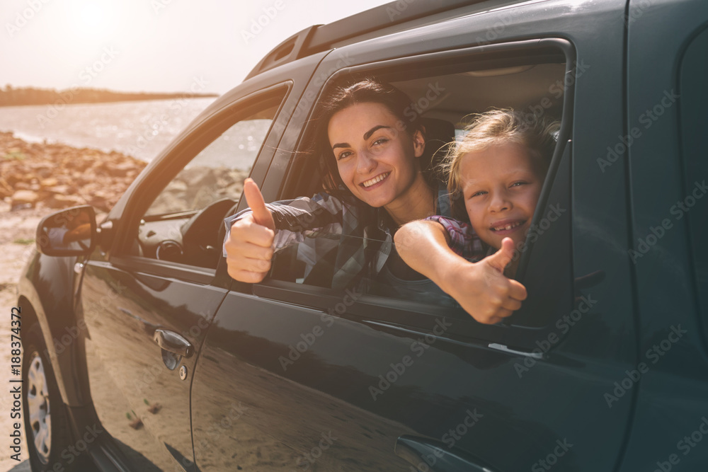 Happy family on a road trip in their car. Dad, mom and daughter are traveling by the sea or the ocean or the river. Summer ride by automobile