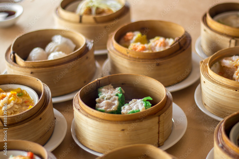 The set of Chinese steamed food in bamboo round flat basket served on the table , the food made from meat such as pork shrimp or fish and can be seen things like these in restaurant. The set of Chinese steamed food in bamboo round flat basket served on the table , the food made from meat such as pork shrimp or fish and can be seen things like these in restaurant.