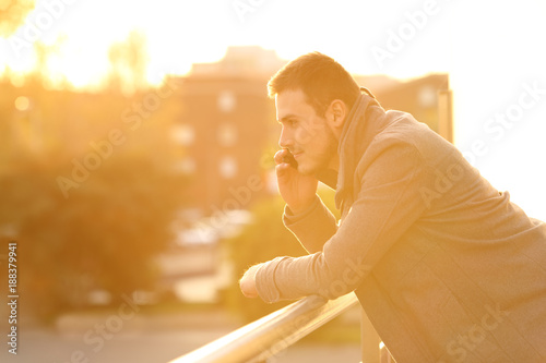 Man talking on phone in a balcony in winter