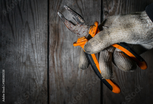 Worker in old gloves holds pliers