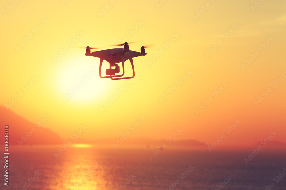 silhouette of flying drone which taking photo over sunrise sea silhouette of flying drone which taking photo over sunrise sea