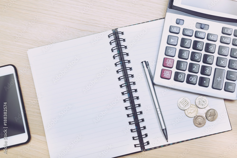 Money (coins), calculator and notebook,notepad,pen on wood table, top view with copy space - financial background concept Money (coins), calculator and notebook,notepad,pen on wood table, top view with copy space - financial background concept