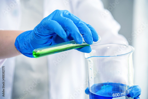 science laboratory researcher perform test with blue and green solution