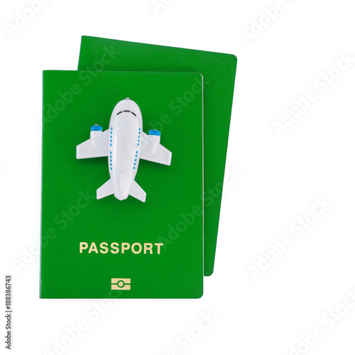 Small toy plane on top of green passports on a white background.