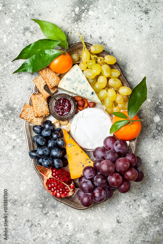 Appetizers table with antipasti snacks. Cheese variety board over grey concrete background. Top view  flat lay