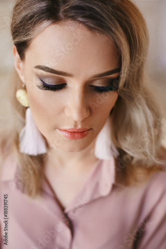 Portrait of beautiful fashionable blonde girl in a blouse with handmade and professional makeup