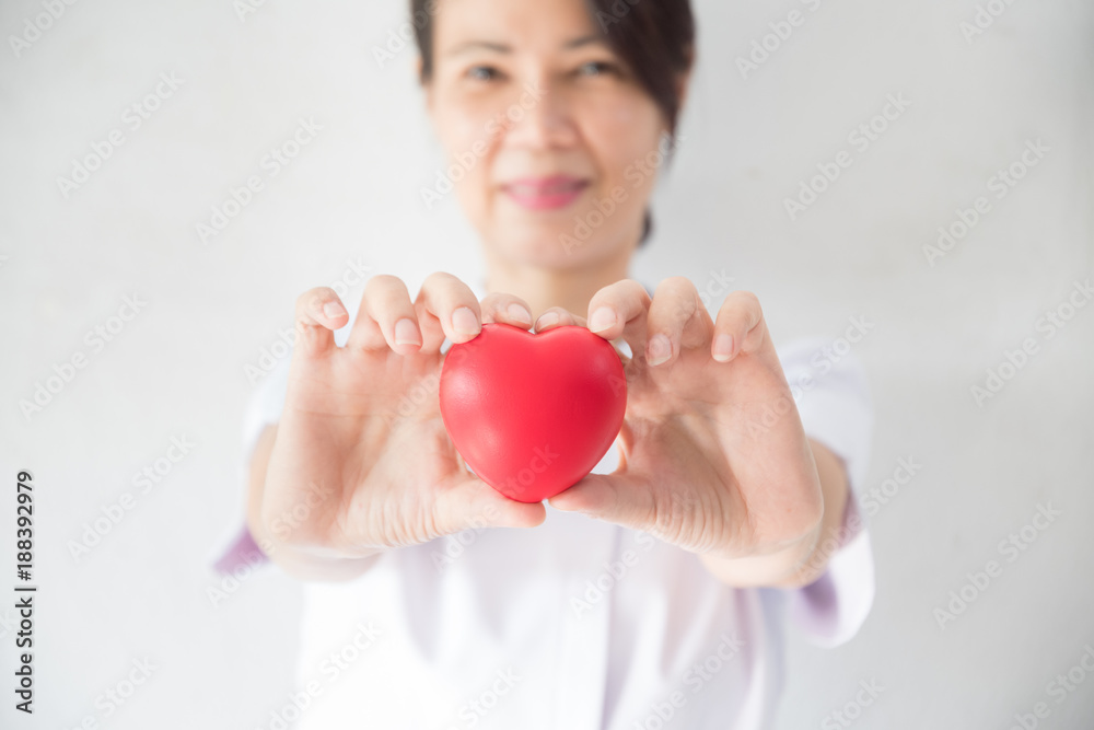 Female nurse holding a red heart shape. Health, Insurance and love concept. Female nurse holding a red heart shape. Health, Insurance and love concept.