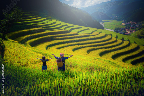 Women farmer and daughter raising arm on Rice fields terraced at sunset in Mu Cang Chai, YenBai, Vietnam.
