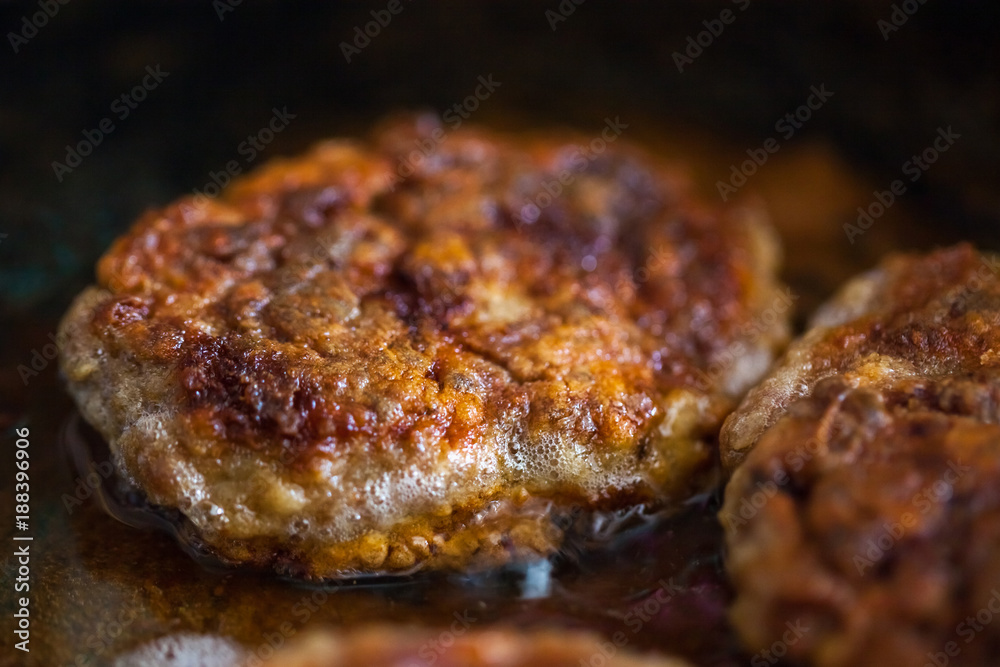 Steaks in a frying pan are roasted on the stove. Fried cutlets