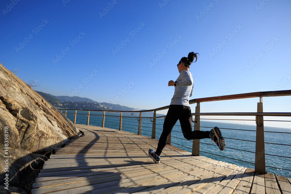 sporty female jogger morning exercise on seaside boardwalk