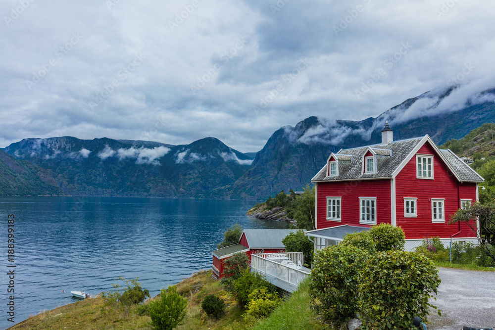 Naklejka premium Wooden red cottage. Stone snowy mountains. Norway.