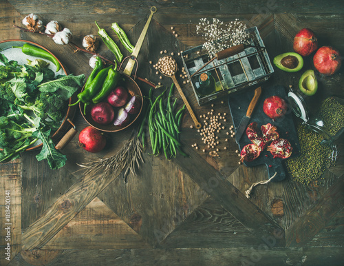 Winter vegetarian food cooking ingredients. Flat-lay of seasonal vegetables and fruit, beans, kitchen utencils over vintage wooden table background, top view, copy space. Healthy, clean eating concept