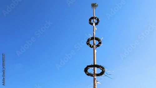 Decoration of a maypole in a small village in Lower Bavaria is rustling in the wind on a sunny day