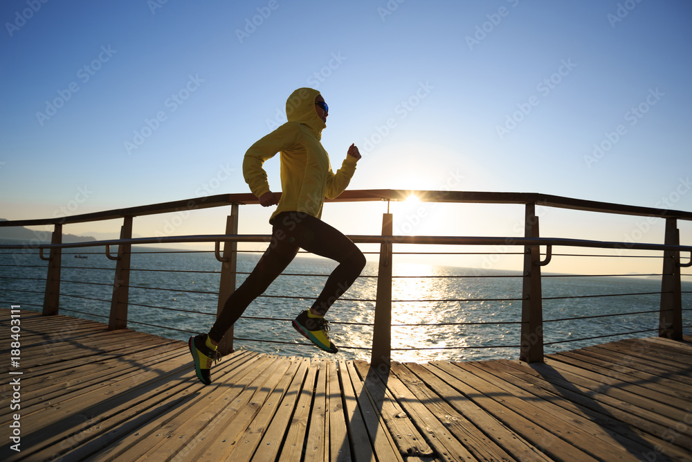 Fototapeta premium sporty female jogger morning exercise on seaside boardwalk during sunrise