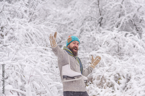 bearded happy man hold skate in snowy winter forest, christmas