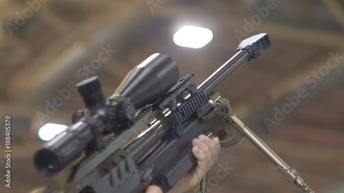 A sniper rifle in the hands of a man, an optical sight, a backdrop, a bokeh. 60 fps photo