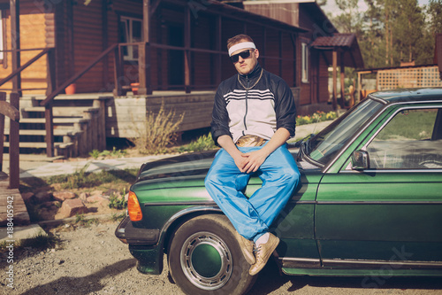 guy in the nineties sitting on the hood of the car