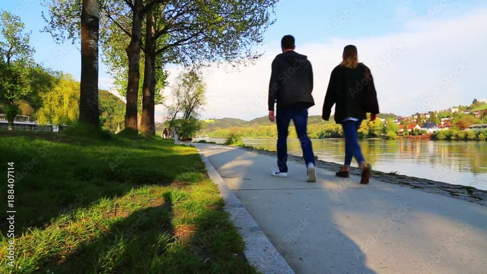 Young couple is walking along river Inn on a sunny day in spring in Passau Young couple is walking along river Inn on a sunny day in spring in Passau