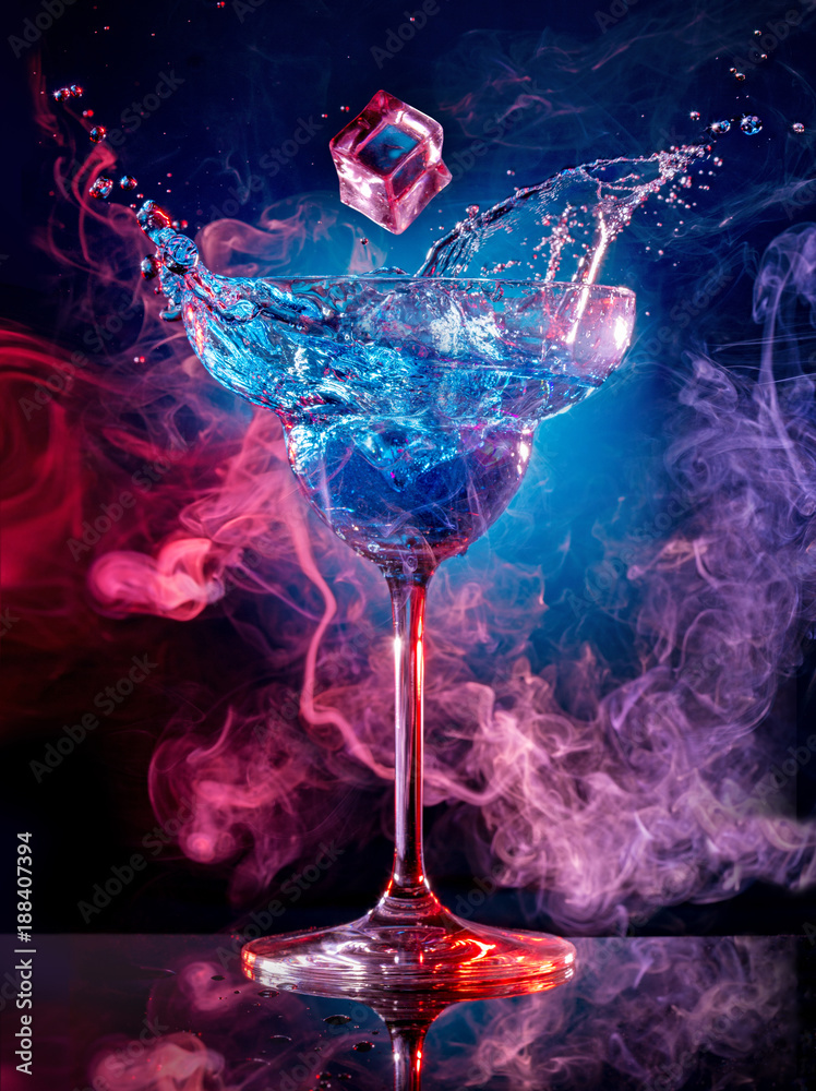 ice cube falling into splashing cocktail on smoky background - obrazy, fototapety, plakaty 