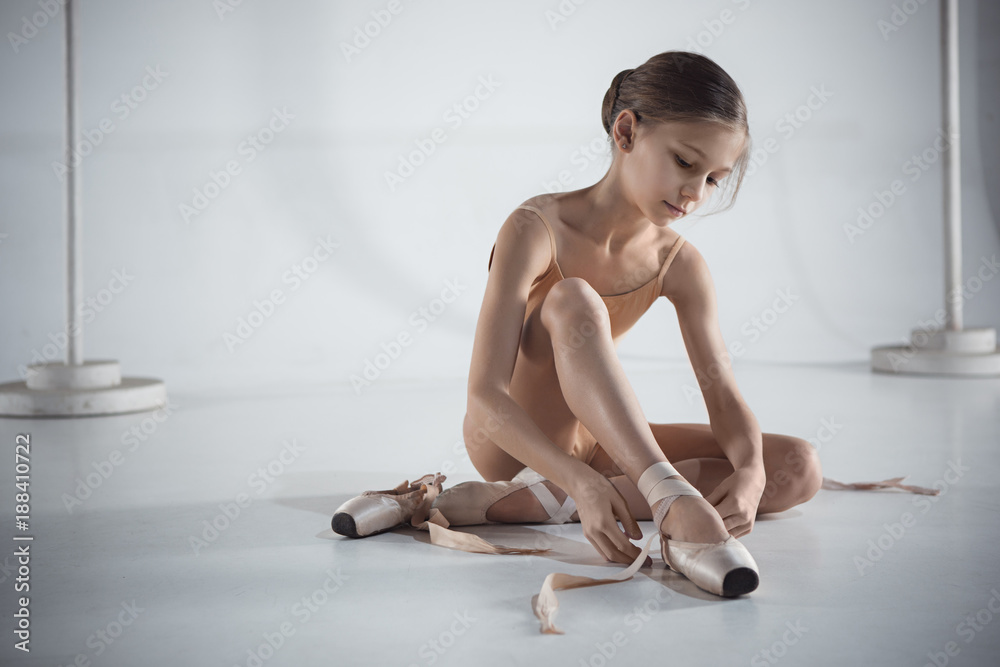Fototapeta premium Beautiful little ballerina puting on foot pointe shoes