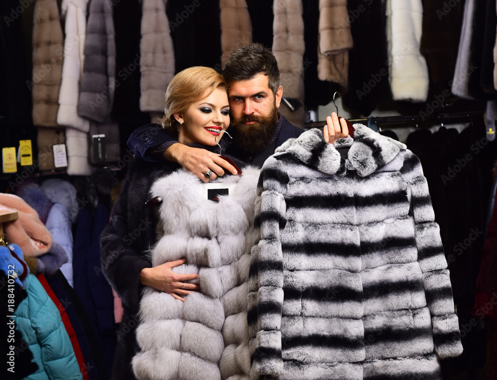 Man with strict face and woman with coats in shop.