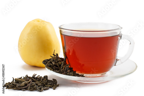 Glass cup of tea on saucer with dry leaves of green tea and apple on white isolated background